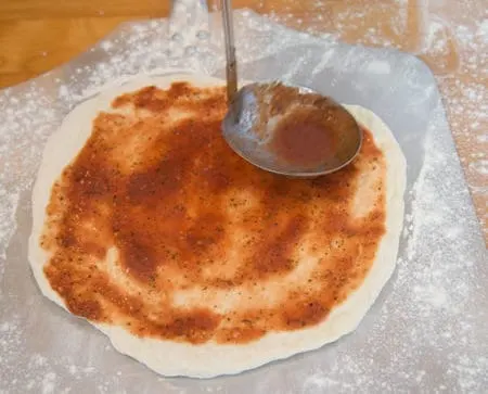 adding pizza sauce